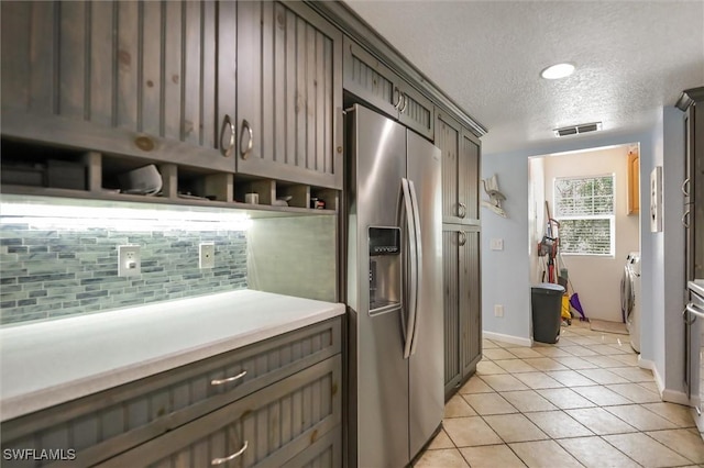20433 Fern Cir, North Fort Myers, FL 33917 - kitchen featuring stainless steel fridge with ice dispenser, washer and dryer, decorative backsplash, a textured ceiling, and light tile patterned floors