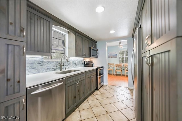 20433 Fern Cir, North Fort Myers, FL 33917 - kitchen featuring appliances with stainless steel finishes, light tile patterned flooring, light countertops, ceiling fan, and healthy amount of natural light