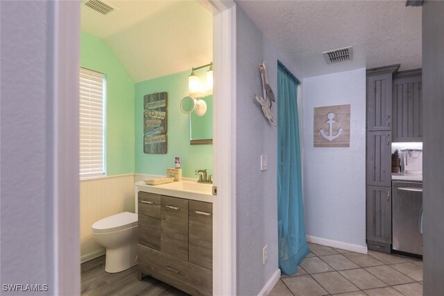 20433 Fern Cir, North Fort Myers, FL 33917 - bathroom featuring vanity, wainscoting, vaulted ceiling, a textured ceiling, and tile patterned flooring