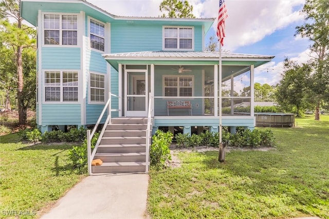 20433 Fern Cir, North Fort Myers, FL 33917 - view of front facade featuring a sunroom, a front yard, a metal roof, and a ceiling fan