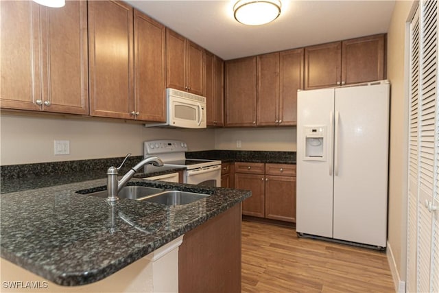 13391 Broadhurst Loop, Fort Myers, FL 33919 - kitchen featuring white appliances, a sink, light wood finished floors, a peninsula, and brown cabinetry