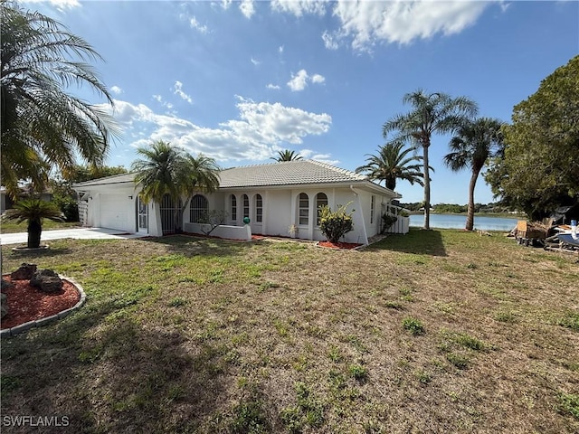 2803 E 5th St, Lehigh Acres, FL 33972 - view of front facade with a garage, a water view, stucco siding, and a front lawn