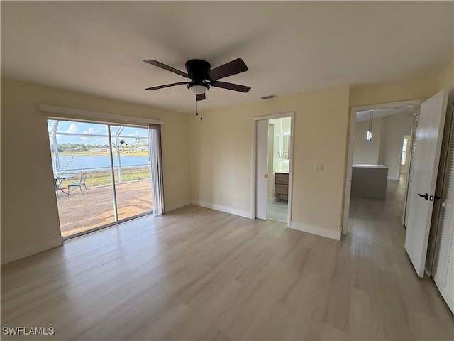 2803 E 5th St, Lehigh Acres, FL 33972 - unfurnished room featuring a water view, a ceiling fan, light wood finished floors, and baseboards