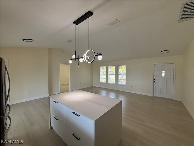 2803 E 5th St, Lehigh Acres, FL 33972 - kitchen with white cabinets, freestanding refrigerator, light wood-style floors, lofted ceiling, and decorative light fixtures