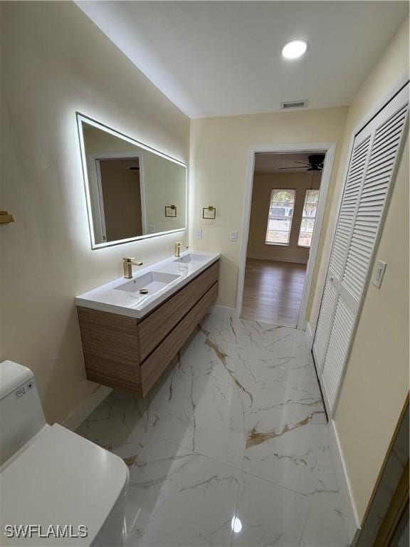 2803 E 5th St, Lehigh Acres, FL 33972 - full bathroom featuring baseboards, double vanity, toilet, marble finish floors, and recessed lighting