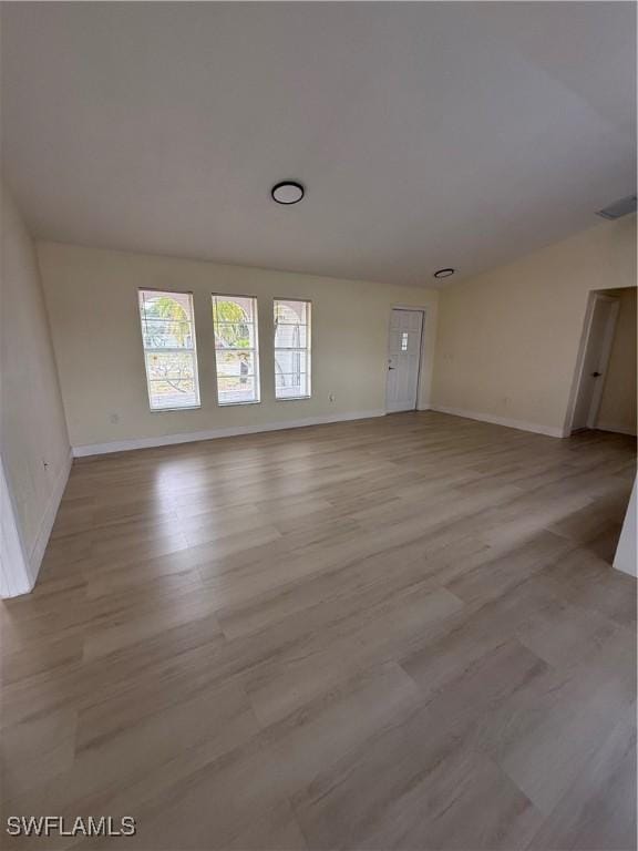 2803 E 5th St, Lehigh Acres, FL 33972 - unfurnished living room featuring light wood finished floors and baseboards