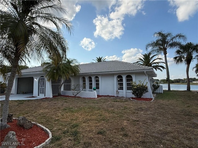 2803 E 5th St, Lehigh Acres, FL 33972 - view of front facade with stucco siding, a front yard, a water view, a garage, and a tiled roof
