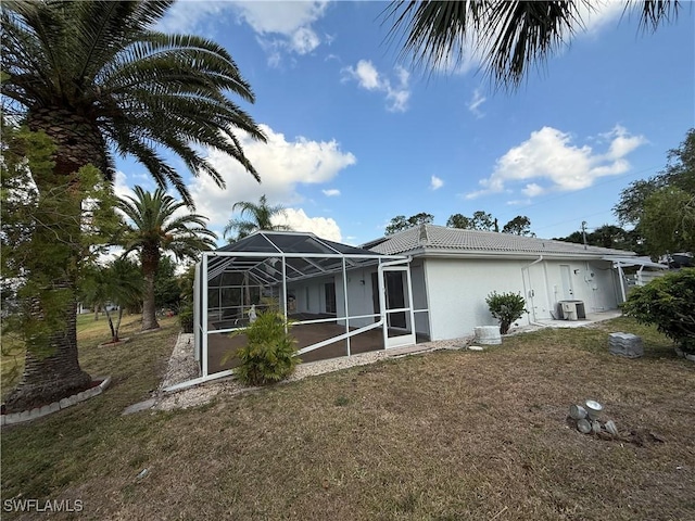 2803 E 5th St, Lehigh Acres, FL 33972 - back of property featuring stucco siding, a lawn, a lanai, a tile roof, and central AC