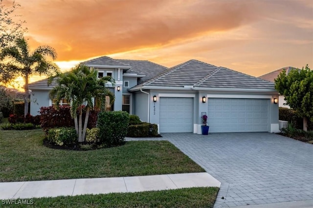 14372 Neptune Ave, Naples, FL 34114 - view of front of home with a garage, decorative driveway, stucco siding, a front yard, and a tiled roof