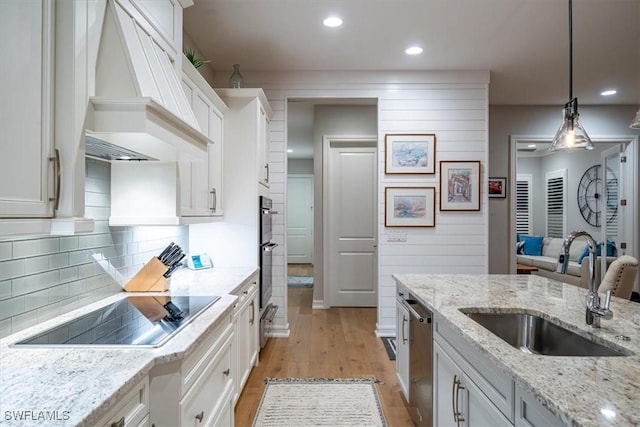 14372 Neptune Ave, Naples, FL 34114 - kitchen with black electric cooktop, a sink, premium range hood, white cabinetry, and light wood-type flooring