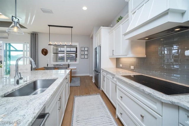 14372 Neptune Ave, Naples, FL 34114 - kitchen with premium range hood, black electric cooktop, a sink, stainless steel fridge, and backsplash