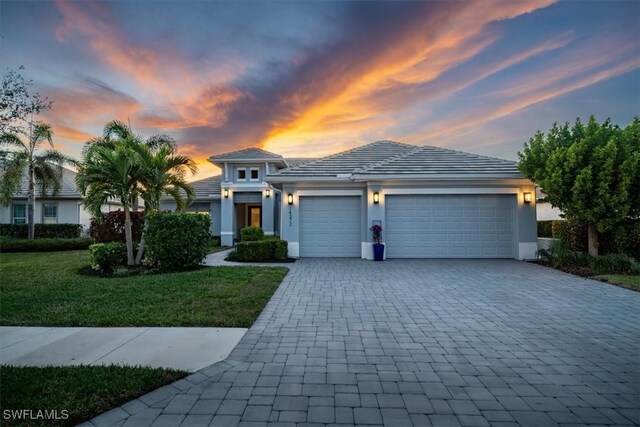 14372 Neptune Ave, Naples, FL 34114 - view of front of home featuring decorative driveway, a garage, a front lawn, and stucco siding