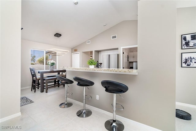 2310 SW 17th St, Cape Coral, FL 33991 - kitchen with freestanding refrigerator, lofted ceiling, a breakfast bar area, baseboards, and light countertops