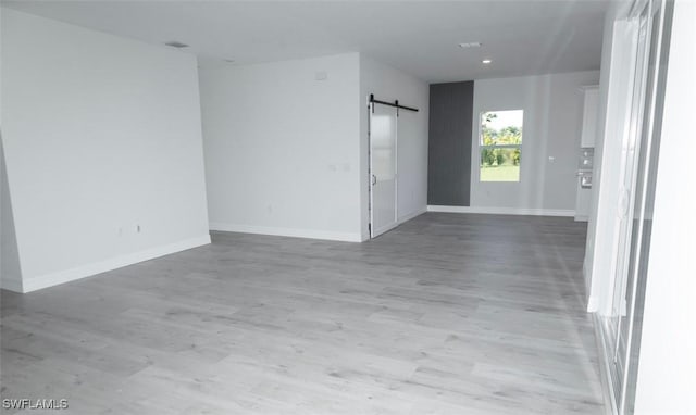 17211 Nile Ct, Punta Gorda, FL 33955 - unfurnished room with a barn door, light wood finished floors, baseboards, and recessed lighting