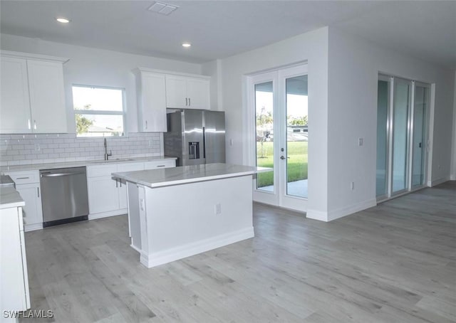 17211 Nile Ct, Punta Gorda, FL 33955 - kitchen with stainless steel appliances, french doors, a sink, a center island, and light wood-style flooring