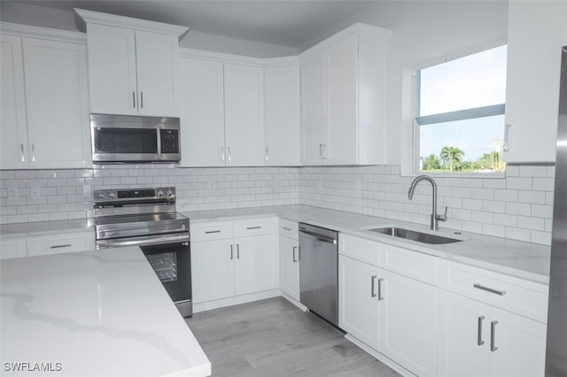 17211 Nile Ct, Punta Gorda, FL 33955 - kitchen featuring stainless steel appliances, a sink, white cabinetry, light wood-style flooring, and light stone countertops