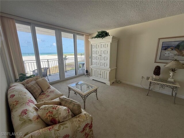 180 Seaview Ct Unit 715, Marco Island, FL 34145 - living area featuring view of water and beach, plenty of natural light, light colored carpet, a textured ceiling, and baseboards