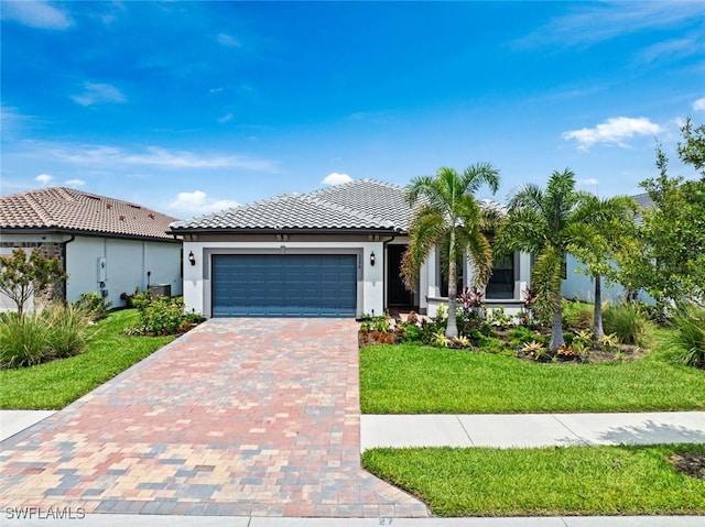 5596 Celebration Dr, Ave Maria, FL 34142 - view of front of property with stucco siding, an attached garage, a tile roof, a front yard, and decorative driveway