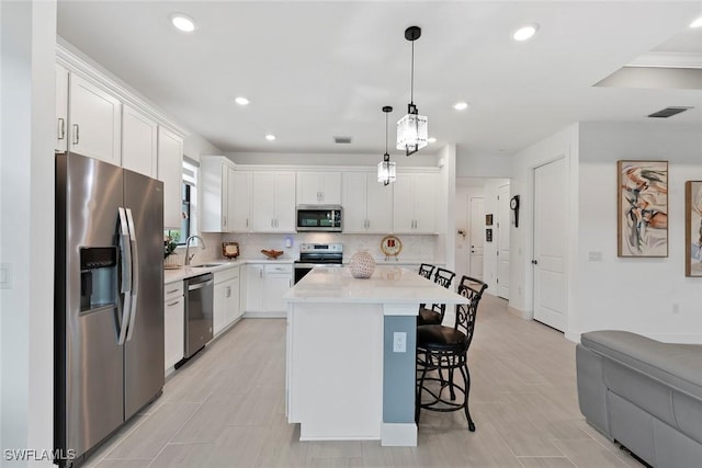 5596 Celebration Dr, Ave Maria, FL 34142 - kitchen featuring stainless steel appliances, a breakfast bar, light countertops, white cabinets, and recessed lighting