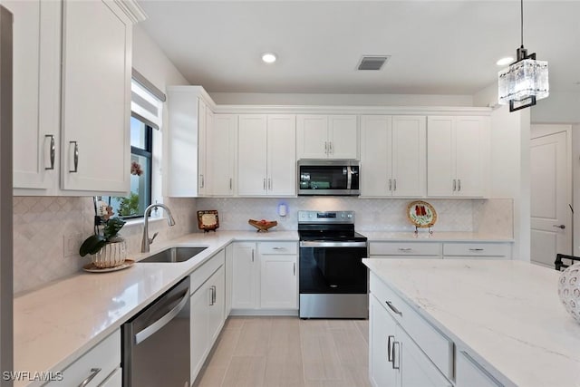 5596 Celebration Dr, Ave Maria, FL 34142 - kitchen with stainless steel appliances, a sink, white cabinetry, and recessed lighting