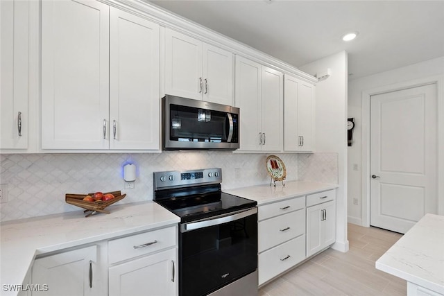 5596 Celebration Dr, Ave Maria, FL 34142 - kitchen with stainless steel appliances, white cabinetry, light stone countertops, tasteful backsplash, and recessed lighting