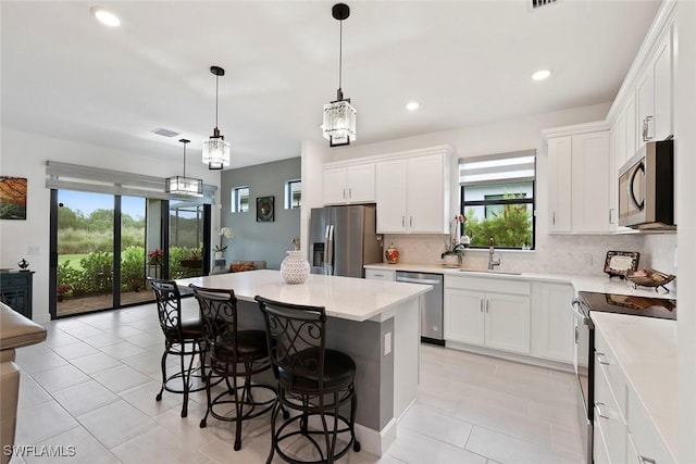 5596 Celebration Dr, Ave Maria, FL 34142 - kitchen featuring stainless steel appliances, a sink, a kitchen breakfast bar, light tile patterned floors, and a center island