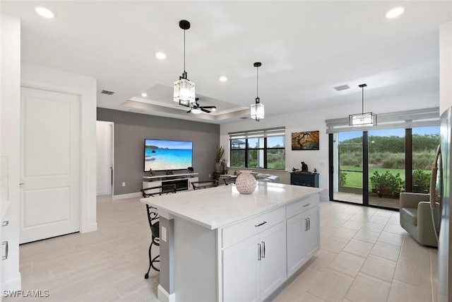 5596 Celebration Dr, Ave Maria, FL 34142 - kitchen with a raised ceiling, recessed lighting, a center island, hanging light fixtures, and light stone countertops