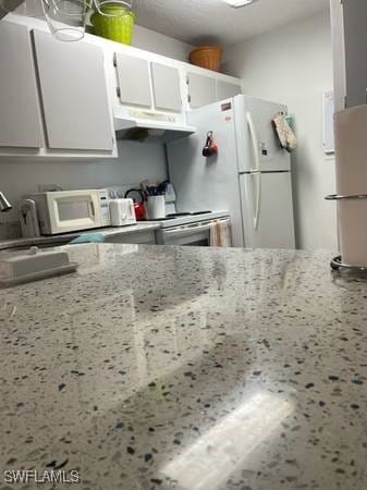 9610 Green Cypress Ln Unit 4, Fort Myers, FL 33905 - kitchen with white cabinets, under cabinet range hood, white appliances, and light stone counters