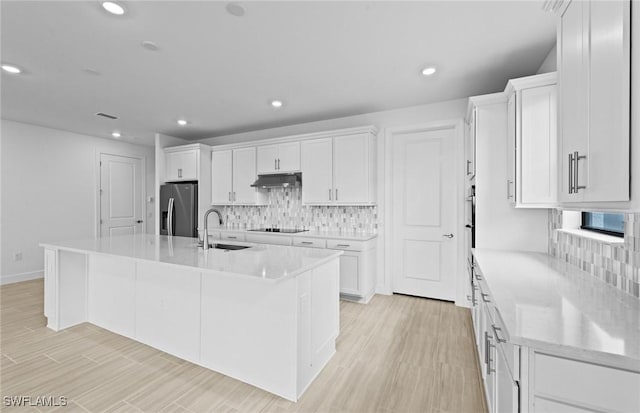 6600 Legacy Way, Ave Maria, FL 34142 - kitchen with stainless steel fridge, a sink, under cabinet range hood, white cabinets, and recessed lighting