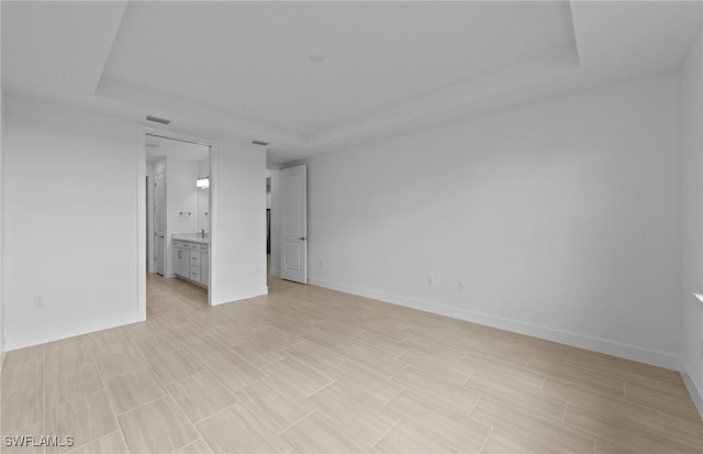 6600 Legacy Way, Ave Maria, FL 34142 - empty room featuring a raised ceiling, baseboards, and light wood-style floors