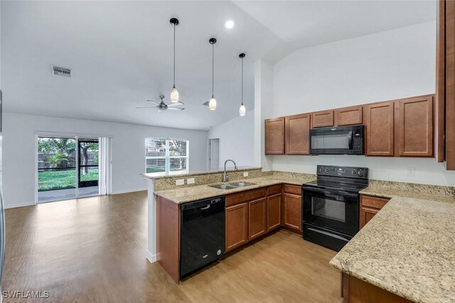 1205 SW 32nd Ter, Cape Coral, FL 33914 - kitchen featuring black appliances, a sink, light wood finished floors, a peninsula, and brown cabinets