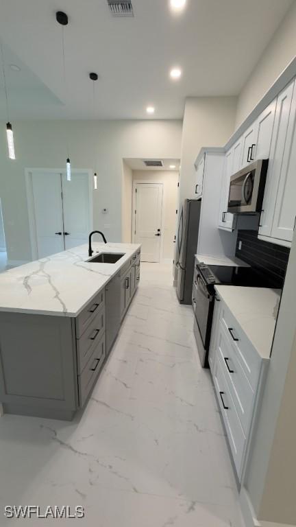 4619 7th St W, Lehigh Acres, FL 33971 - kitchen featuring stainless steel appliances, a sink, a kitchen island with sink, gray cabinets, and light stone counters