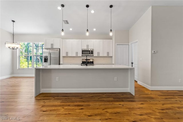 3519 Heron Cove Ct, Bonita Springs, FL 34134 - kitchen with appliances with stainless steel finishes, light countertops, a large island with sink, wood finished floors, and white cabinetry