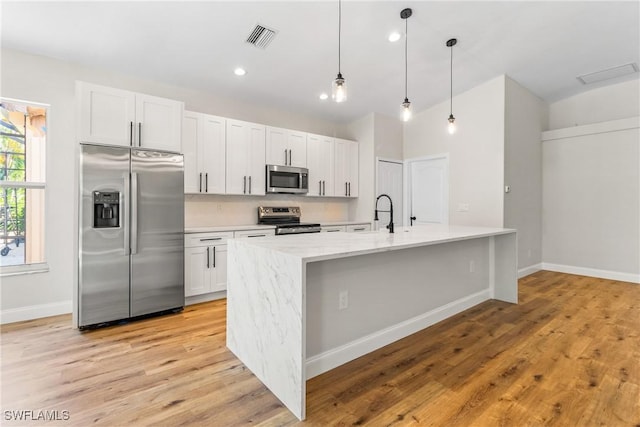 3519 Heron Cove Ct, Bonita Springs, FL 34134 - kitchen with stainless steel appliances, light wood-style floors, white cabinetry, decorative light fixtures, and baseboards