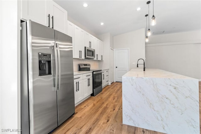 3519 Heron Cove Ct, Bonita Springs, FL 34134 - kitchen featuring stainless steel appliances, white cabinetry, light wood-style floors, recessed lighting, and light stone counters