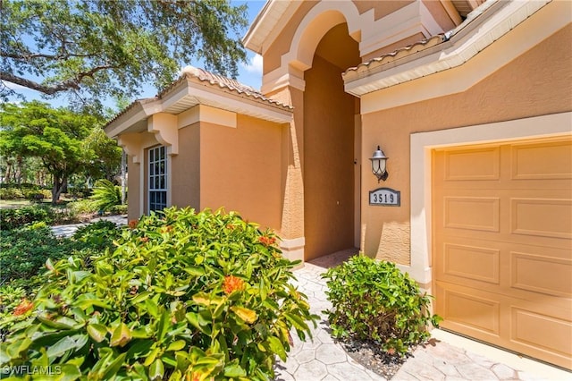 3519 Heron Cove Ct, Bonita Springs, FL 34134 - view of exterior entry featuring stucco siding, a tile roof, and an attached garage