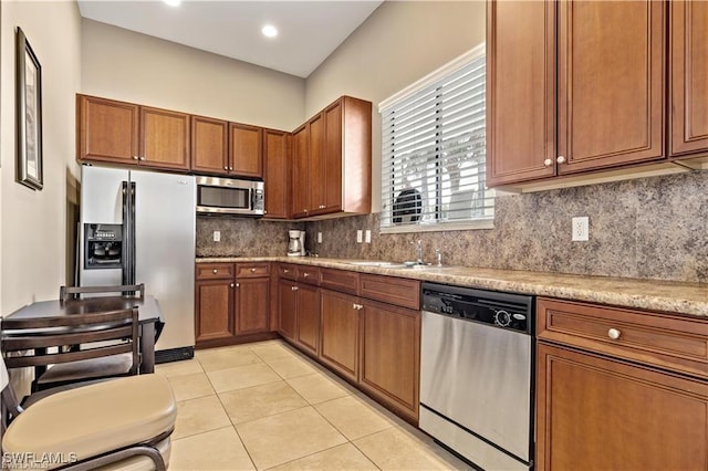 9440 Sardinia Way Unit 110, Fort Myers, FL 33908 - kitchen featuring stainless steel appliances, brown cabinets, a sink, light countertops, and light tile patterned floors
