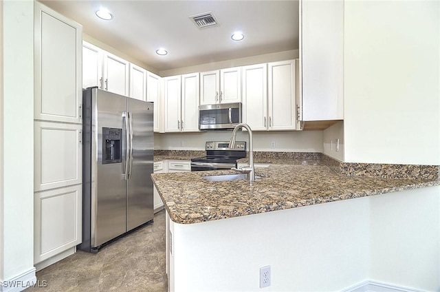 9440 Sardinia Way Unit 110, Fort Myers, FL 33908 - kitchen featuring appliances with stainless steel finishes, a peninsula, white cabinets, dark stone counters, and recessed lighting