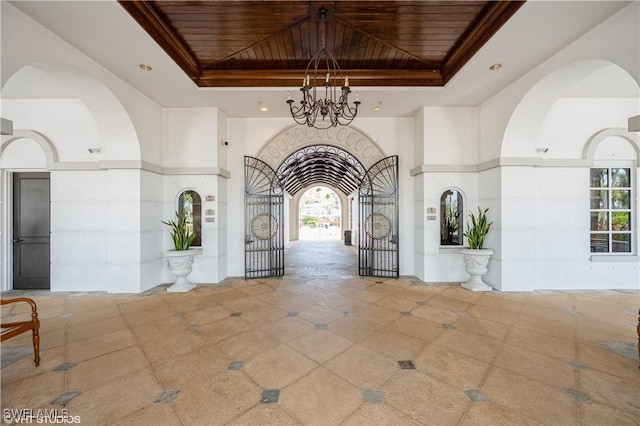 4610 Hawks Nest Dr Unit A104, Naples, FL 34114 - entrance foyer with a tray ceiling, wood ceiling, a chandelier, and arched walkways
