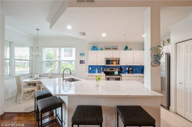 4610 Hawks Nest Dr Unit A104, Naples, FL 34114 - kitchen featuring stainless steel appliances, a sink, ornamental molding, a breakfast bar, and white cabinets