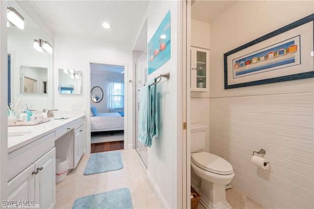 4610 Hawks Nest Dr Unit A104, Naples, FL 34114 - ensuite bathroom featuring double vanity, tile patterned floors, toilet, tile walls, and a shower with shower door