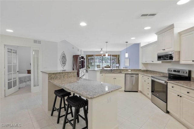 8565 Via Garibaldi Cir Unit 104, Estero, FL 33928 - kitchen with stainless steel appliances, a peninsula, light tile patterned floors, a kitchen breakfast bar, and light stone countertops