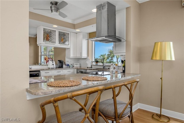 430 Cove Tower Dr Unit 501, Naples, FL 34110 - kitchen featuring ventilation hood, a peninsula, ornamental molding, light stone counters, and white cabinetry