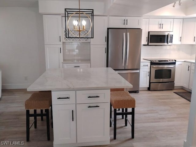 5116 Coronado Pkwy Unit 16, Cape Coral, FL 33904 - kitchen featuring stainless steel appliances, tasteful backsplash, light stone countertops, a chandelier, and white cabinetry