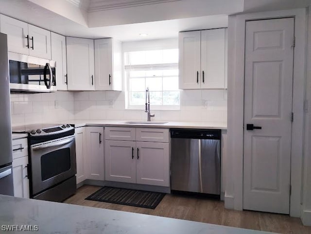 5116 Coronado Pkwy Unit 16, Cape Coral, FL 33904 - kitchen featuring stainless steel appliances, a sink, wood finished floors, backsplash, and crown molding
