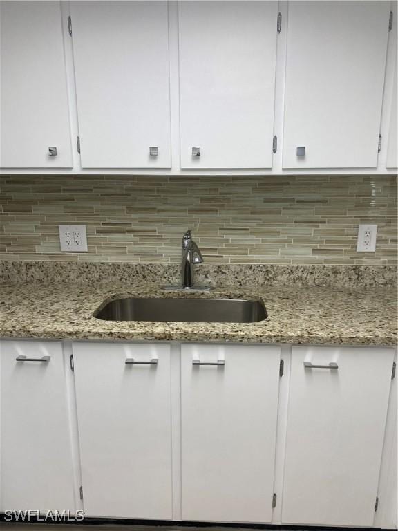 1516 Tropic Ter Unit 1516, North Fort Myers, FL 33903 - kitchen view of white cabinetry, a sink, tasteful backsplash, and light stone counters