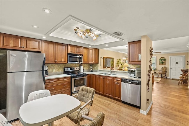 8411 Charter Club Cir Unit 1, Fort Myers, FL 33919 - kitchen featuring appliances with stainless steel finishes, a sink, crown molding, a raised ceiling, and brown cabinetry