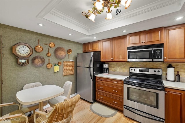 8411 Charter Club Cir Unit 1, Fort Myers, FL 33919 - kitchen with appliances with stainless steel finishes, crown molding, recessed lighting, light wood-style flooring, and brown cabinets