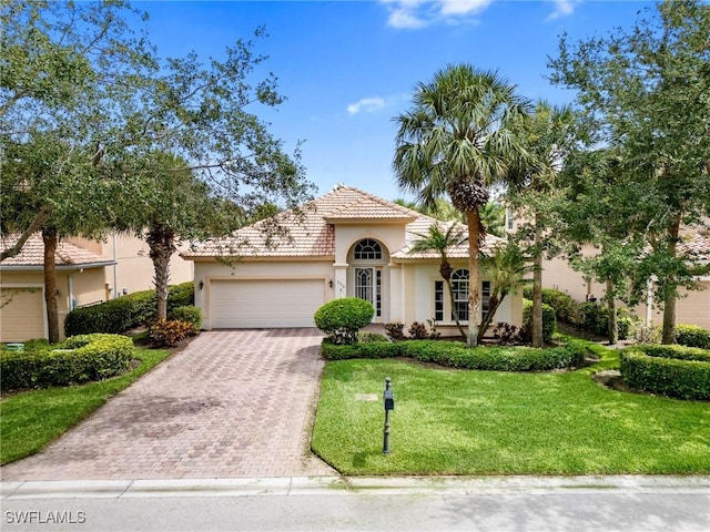 10230 Cobble Hill Rd, Bonita Springs, FL 34135 - mediterranean / spanish house featuring decorative driveway, an attached garage, stucco siding, a front lawn, and a tiled roof