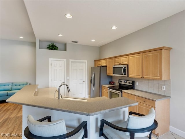 10230 Cobble Hill Rd, Bonita Springs, FL 34135 - kitchen featuring stainless steel appliances, a sink, a kitchen breakfast bar, decorative backsplash, and recessed lighting